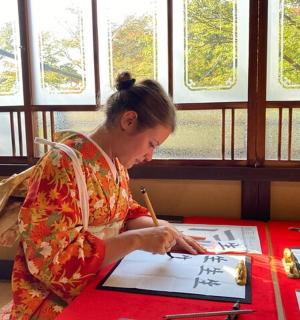 一位身穿和服的女士在桌边写字