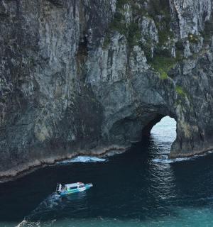 a boat in the water in front of a rock cave