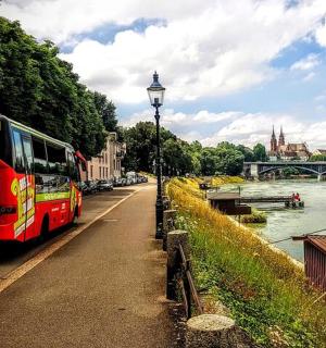 一辆红色巴士沿着河边的道路行驶