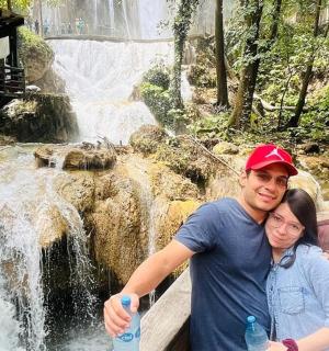 a man and a woman standing in front of a waterfall