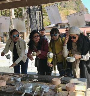 一群人围着一张摆着陶器的桌子