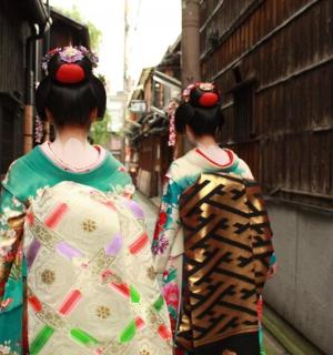 two geisha walking down a street wearing kimonos