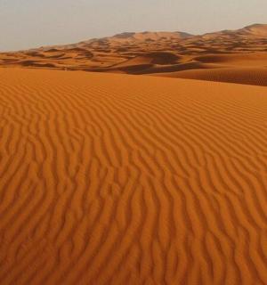 a desert with sand dunes and mountains in the background