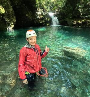 一个小男孩站在瀑布前的河里