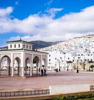 a white building with people walking in front of a city