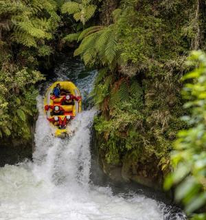 skupina lidí sjíždějících rozbouřenou řeku na raftech