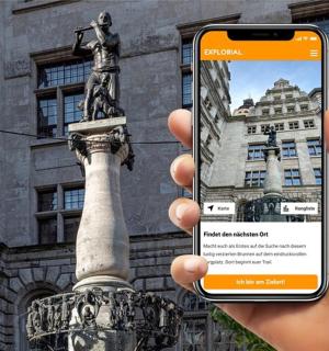 a person holding up a cell phone in front of a statue