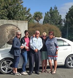 a group of people standing next to a white car