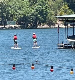 dva lidé na paddleboardech ve vodě s lodí