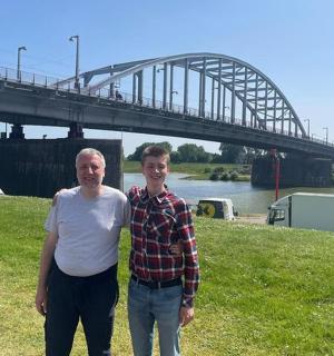 两名男子站在桥边的草地上