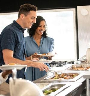 muž a žena stojící v kuchyni a připravující jídlo