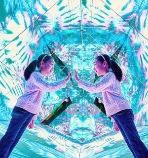 two girls are standing in front of a kaleidoscope
