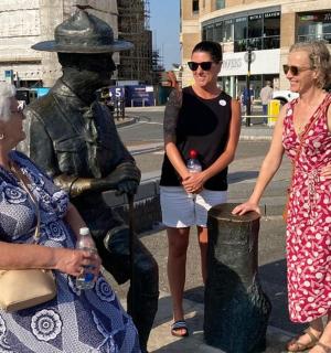 three women are standing next to a statue