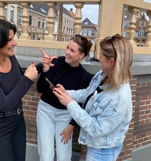 three women standing next to each other looking at a cell phone