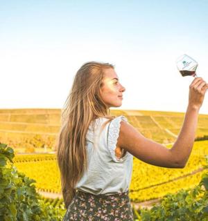 一位女士站在葡萄园里，手里拿着一瓶葡萄酒