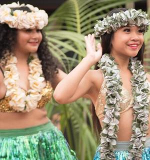 两个头戴鲜花、身穿裙子的女人