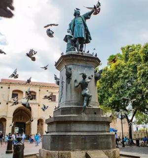פסל מול בניין עם ציפורים עפות סביבו