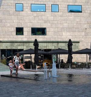 一位女士站在一栋建筑前的喷泉旁