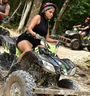 一名女子在泥土中骑着四轮车