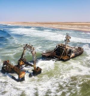 a boat in the ocean with two dredgers in the water
