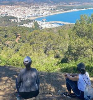 two statues sitting on top of a hill overlooking a city