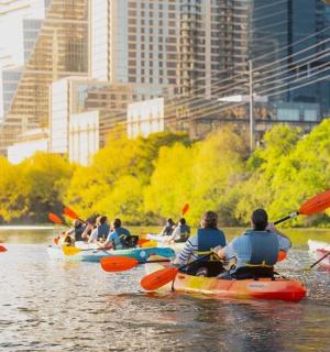 a group of people kayaking down a river in a city