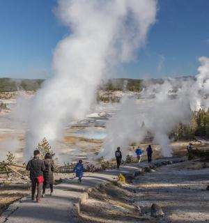 a group of people walking around a geyser