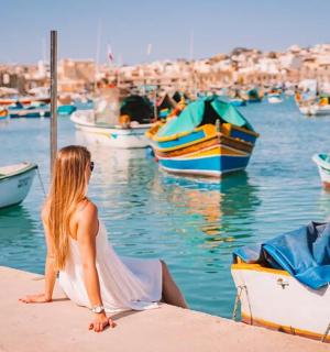 一位女士坐在码头上，看着水中的船只