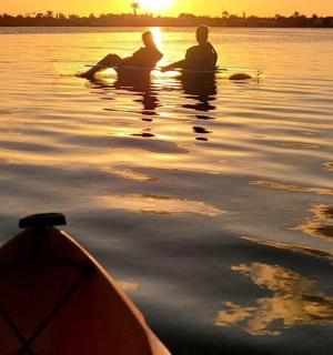 two people sitting in the water next to a kayak