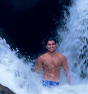 一名男子站在瀑布前的水中