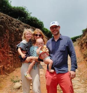 a man and woman standing on a dirt road holding a baby