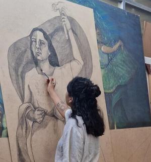 一位女士正在墙上画壁画