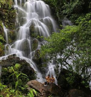 两个人坐在瀑布前的岩石上