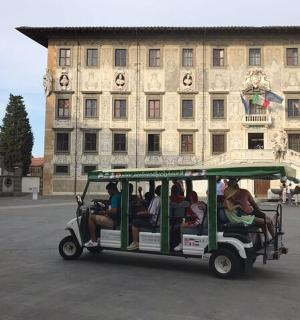 sekumpulan orang menaiki kereta golf di hadapan sebuah bangunan