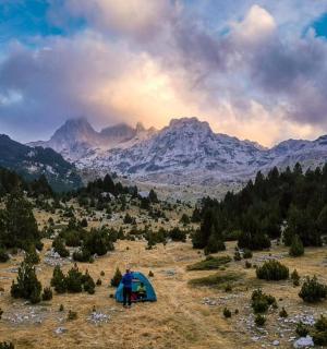 a tent in a field with mountains in the background