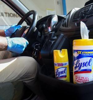 戴着手套驾驶装有汽车清洁剂的汽车的人