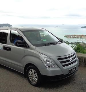 a silver van parked on a road near the ocean