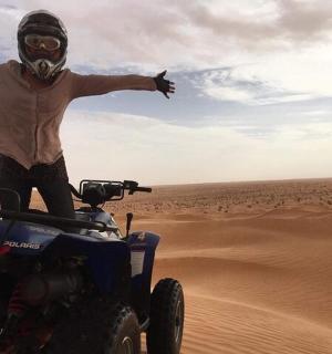 一名男子站在沙漠中的一辆轮车上