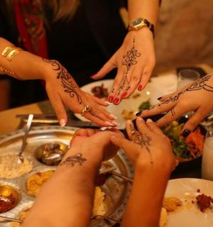 一群人围坐在桌旁，手上涂着指甲花