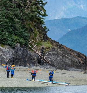 skupina lidí jdoucích po pláži s lodí