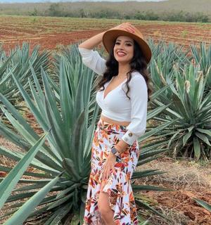 a woman in a hat standing in a pineapple field