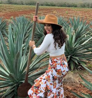 a woman in a hat holding a large wooden shovel