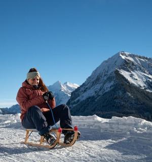 Žena sedí na saních ve sněhu