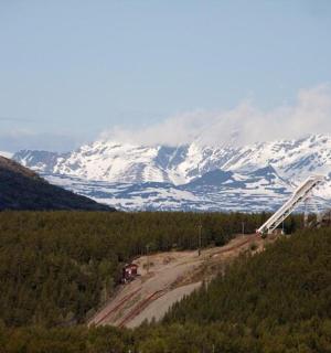 a dirt road in front of a snow covered mountain