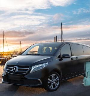 一辆黑色货车停在停满船只的码头旁边