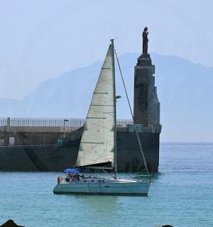 a sail boat in the water next to a statue