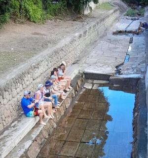 skupina lidí sedících na zdi poblíž vodní hladiny