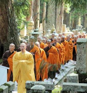 一群身穿橙色长袍的僧侣穿过墓地