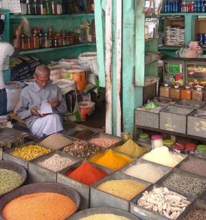 a man sitting in front of a market selling spices