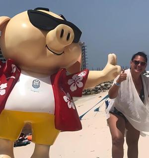 一位女士站在海滩上一个大型充气动物旁边